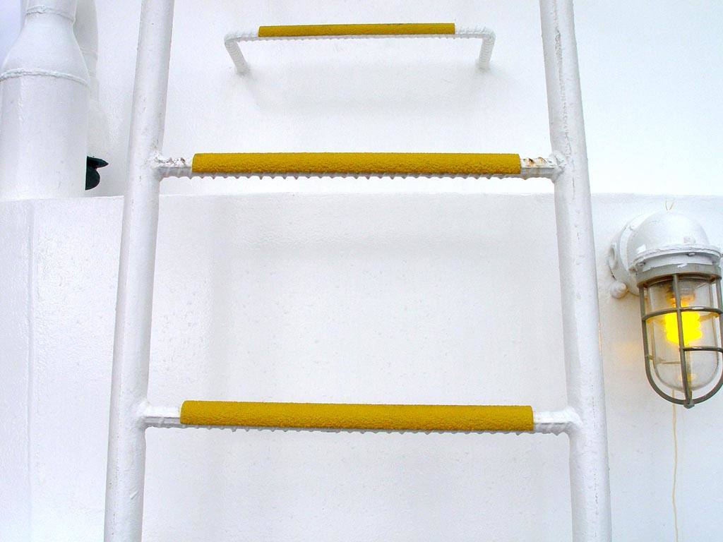 Yellow Anti-slip ladder rung covers are installed over a white rebar ladder on an ocean vessel